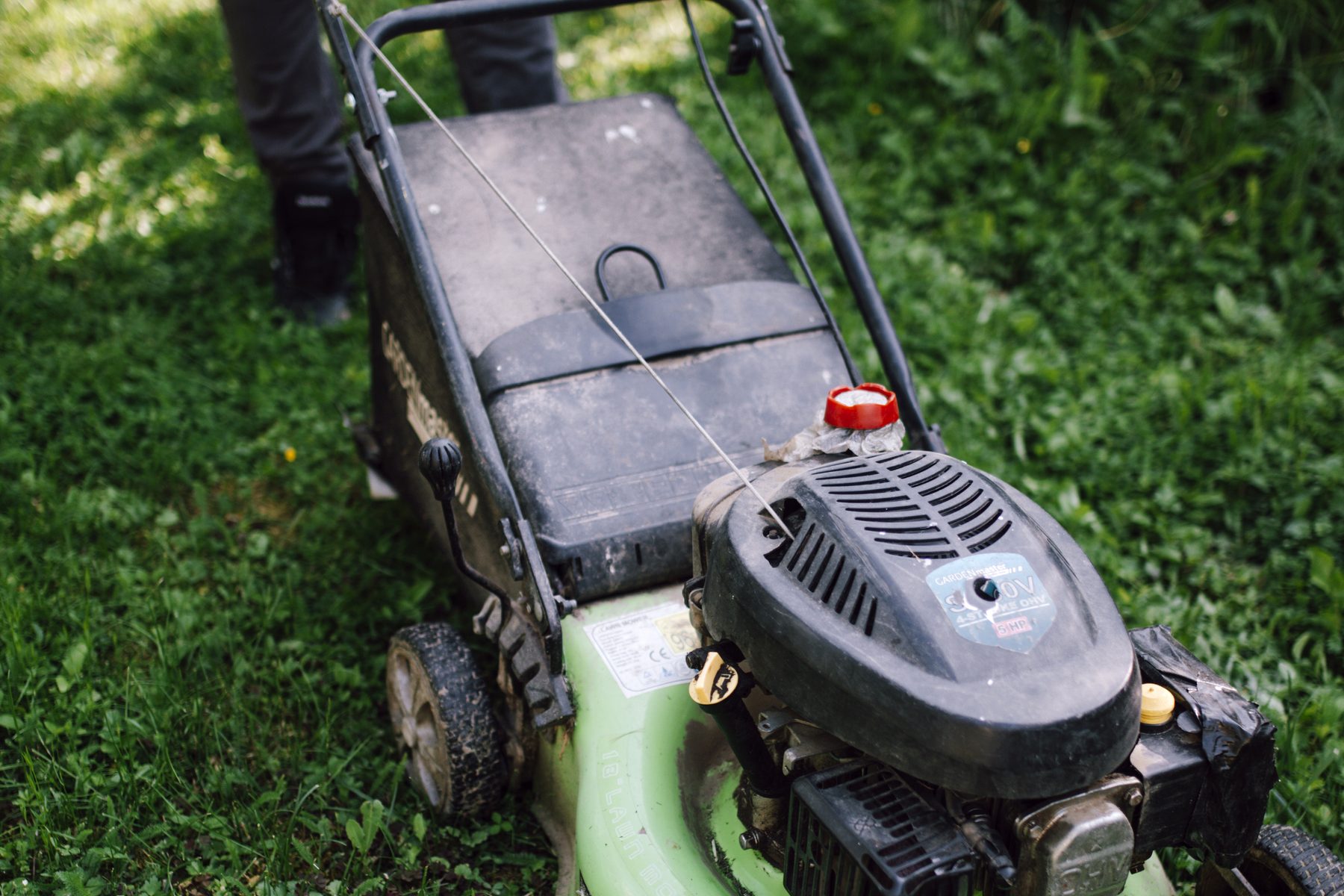 A lawn care crew member mowing a sunny backyard lawn