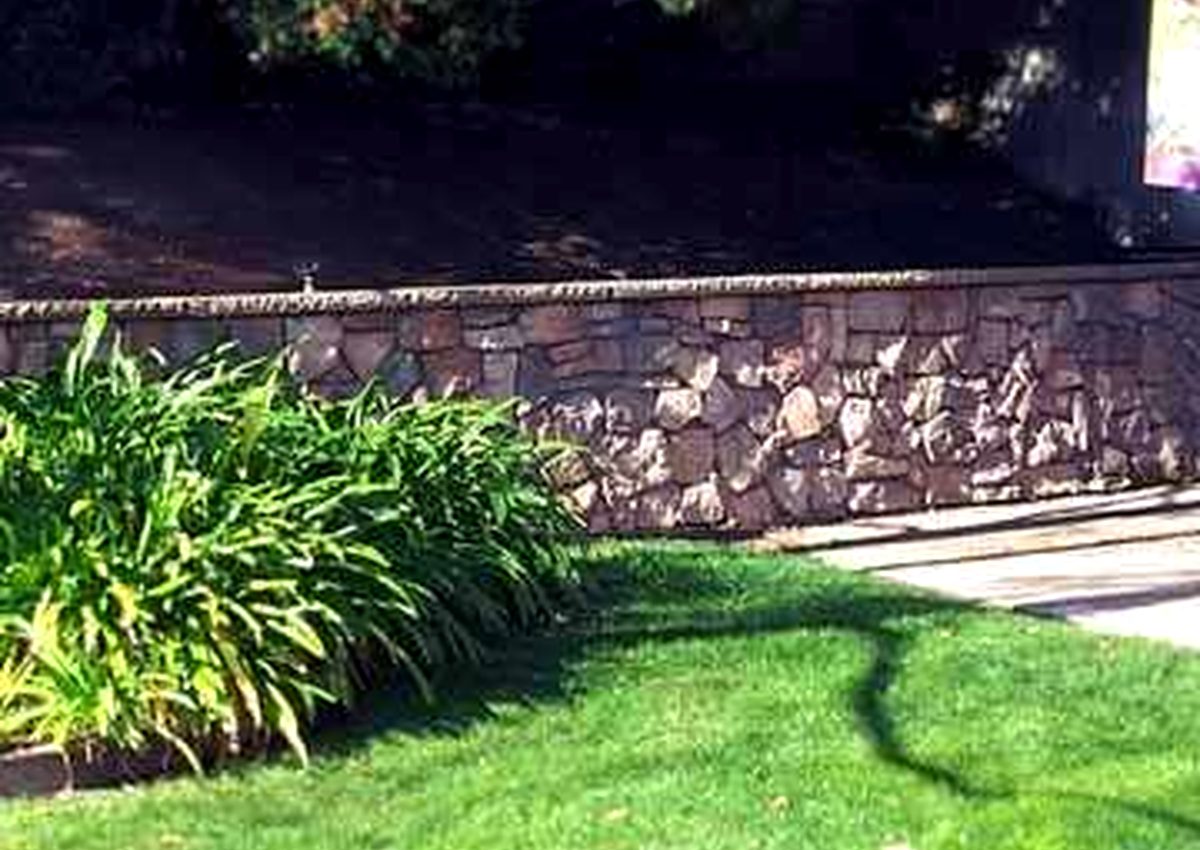 Natural stone retaining wall beside landscaping
